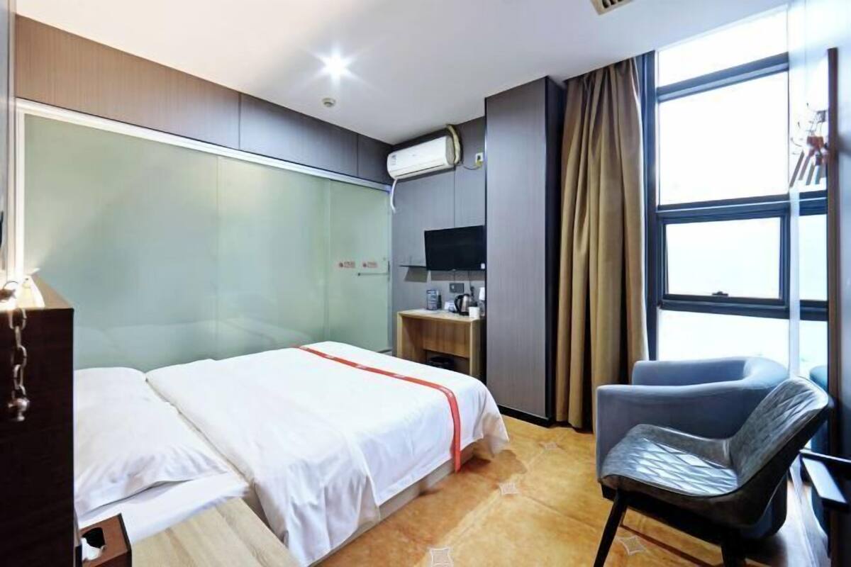 Une chambre d’hôtel équipée d’un lit, d’une chaise, d’un bureau, d’une télévision et d’un appareil de climatisation.