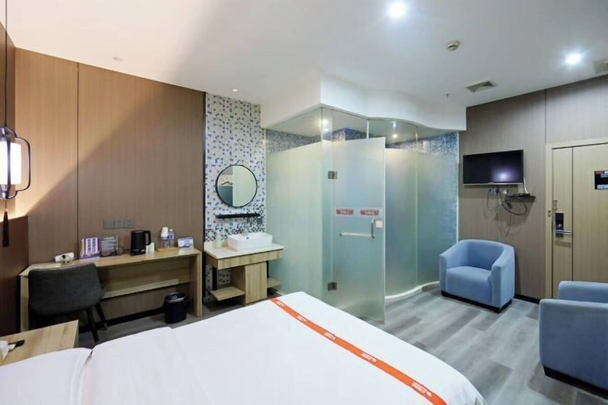 Une chambre d’hôtel équipée d’un lit, d’un bureau, d’une chaise, d’une douche et d’un téléviseur.