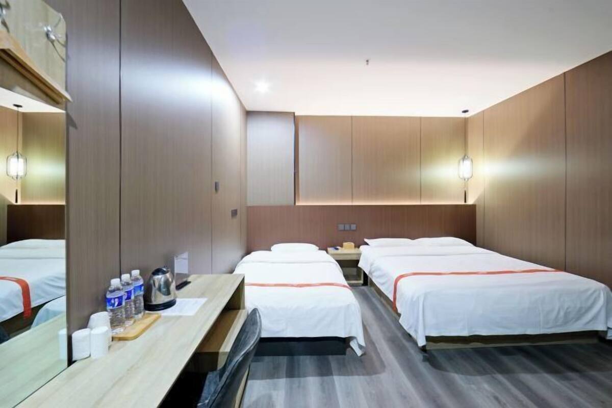 Une chambre d’hôtel avec deux lits, un bureau, un miroir et une table de chevet.