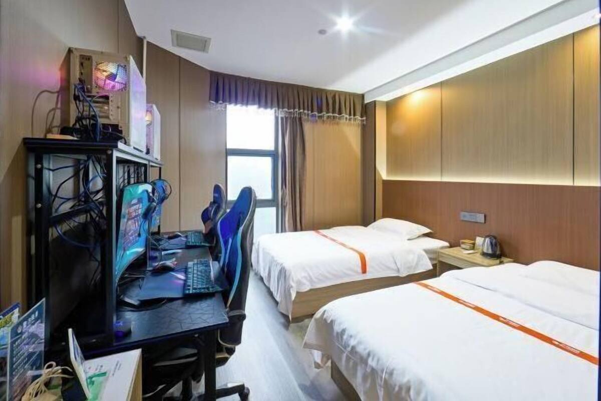 Une chambre d’hôtel équipée d’un bureau, de deux lits, d’un ordinateur et d’une fenêtre.