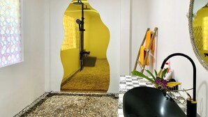 Een badkamer met een gele wand, een zwarte wastafel en een spiegel.