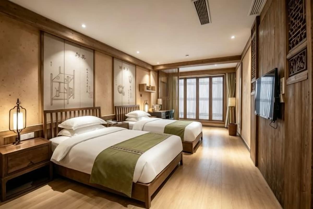 Une chambre d’hôtel avec deux lits, un plancher en bois, une télévision et un décor traditionnel.