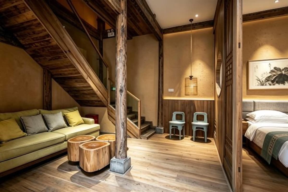 Une pièce avec un escalier en bois, un canapé, un lit et un plancher en bois.