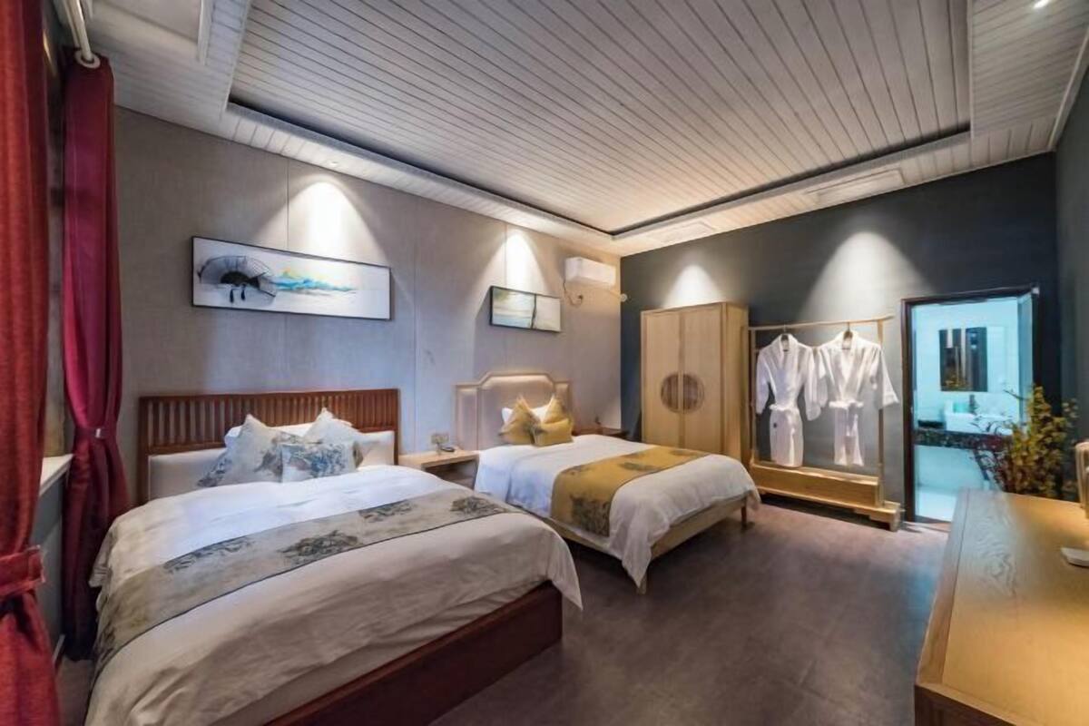 A hotel room with two beds, a wardrobe, a mirror, and a view of the outside.