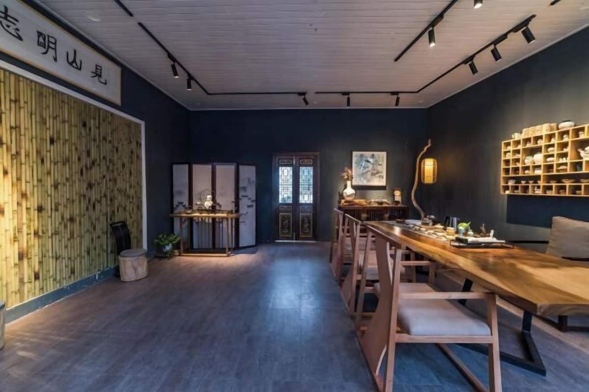 A room with a long wooden table, chairs, a bookshelf, and a traditional door.