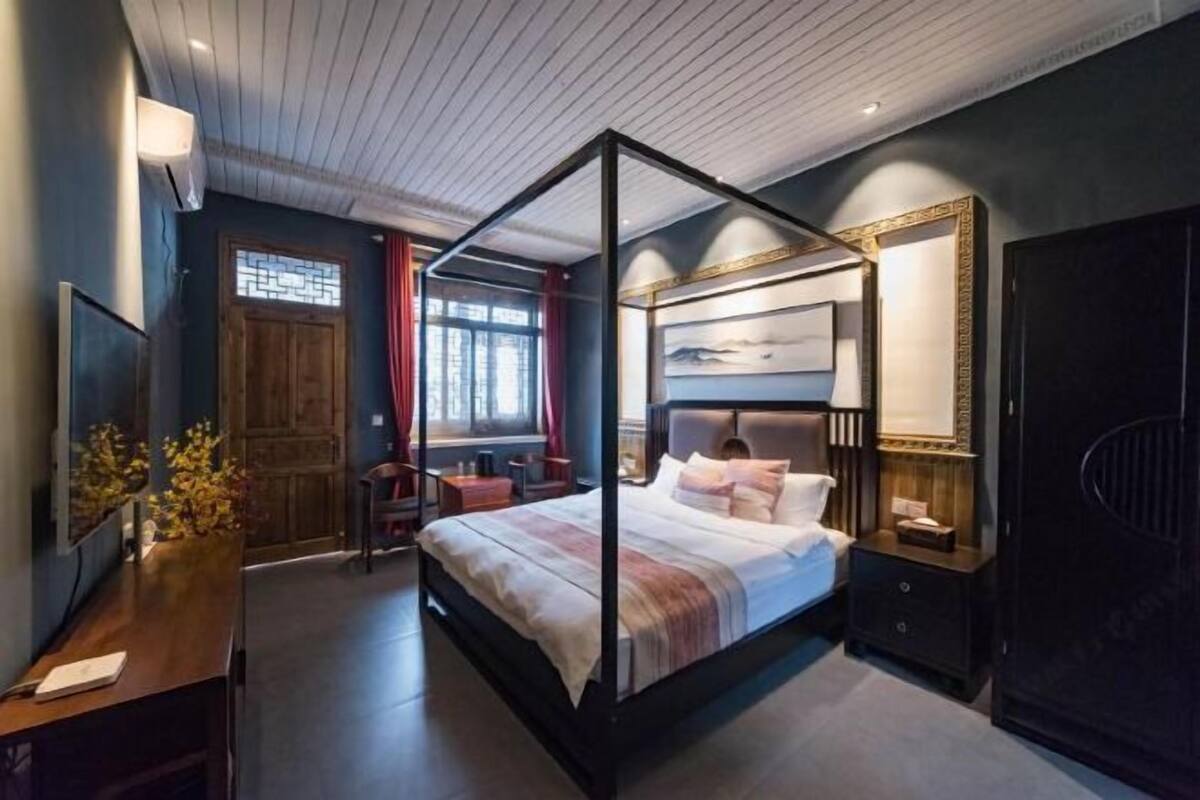 A four-poster bed with a nightstand, a bedside table, and a mirror.