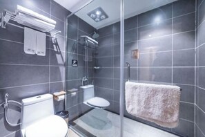 Un baño moderno con cabina de ducha de vidrio, inodoro y lavamanos.
