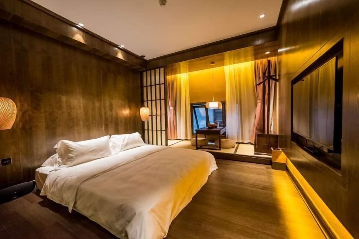 A bedroom with a bed, bedside lamps, a TV, and a mirror.