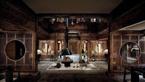 A traditional interior with wooden walls, a central fire pit, and round mirrors.