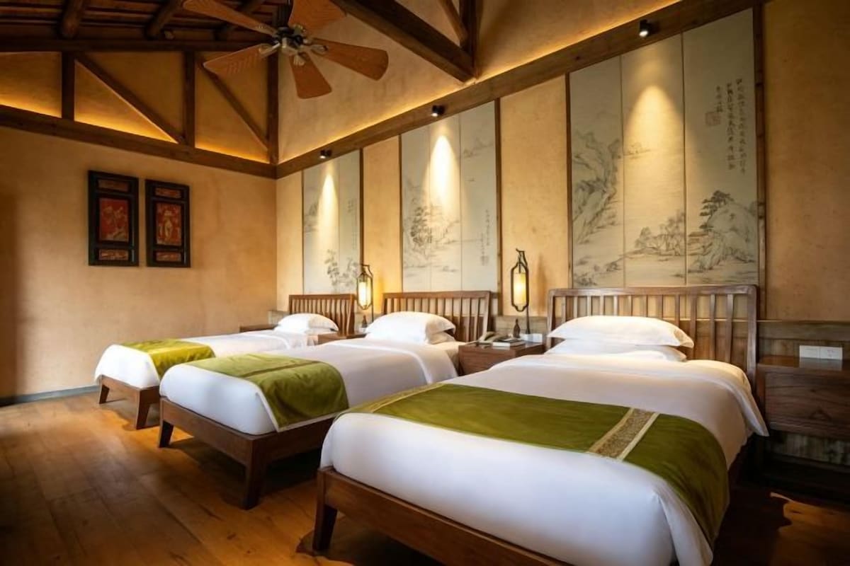 Une chambre d’hôtel avec deux lits, des têtes de lit en bois et des œuvres d’art traditionnelles accrochées aux murs.