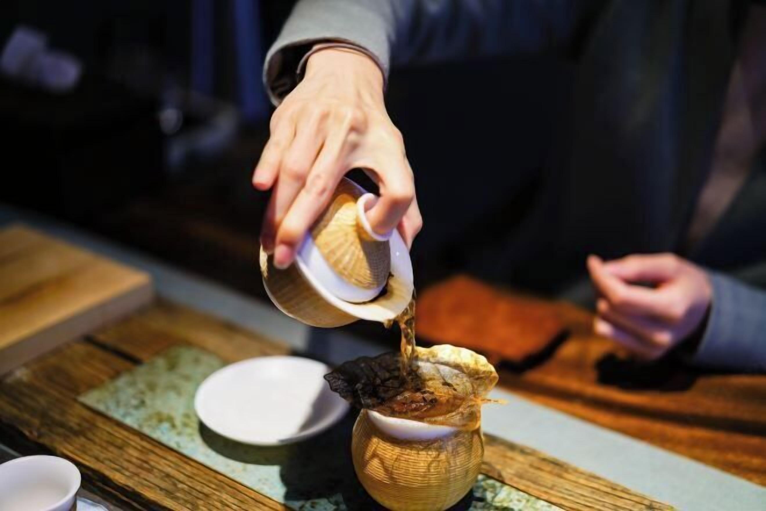 A person pouring a liquid from a bowl into a container.