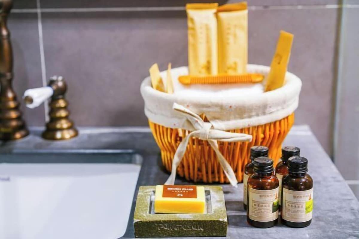 Een badkamer met een zeepbakje, een zeepstaaf en verschillende flessen Seven Plus body wash.