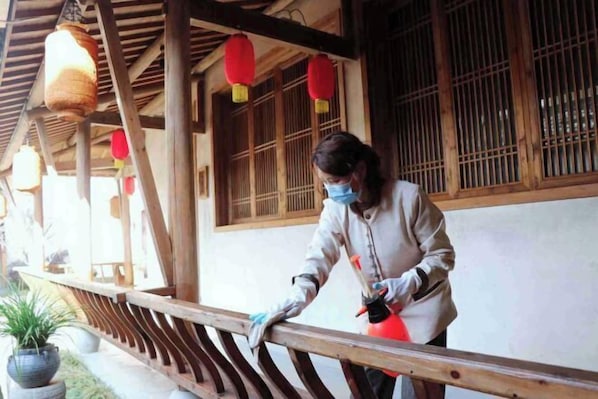 Una persona limpiando un pasamanos de madera con un bote rojo de aerosol.