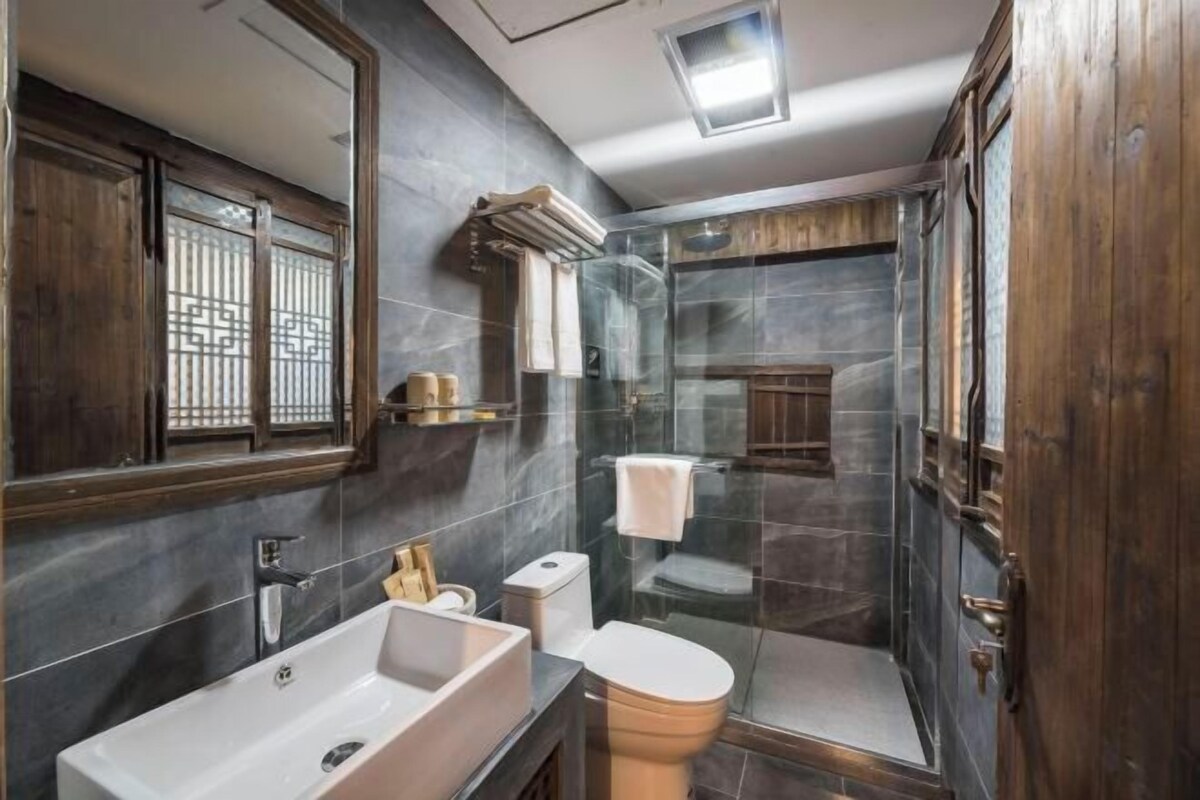 Een moderne badkamer met een groot wastafelmeubel, toilet en een douchecabine van glas.