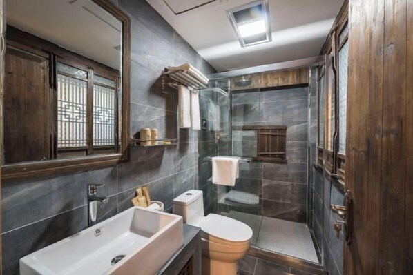 Un baño moderno con un lavamanos grande, inodoro y cabina de ducha de vidrio.