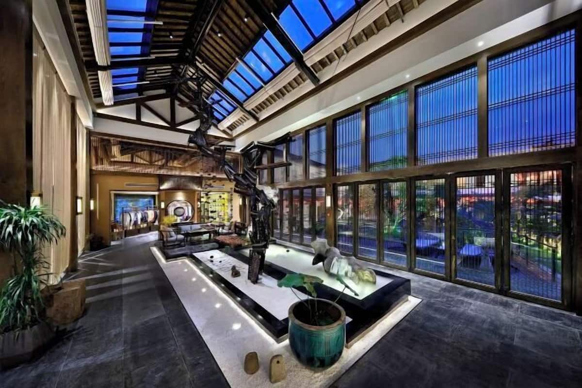 A spacious lobby with a high ceiling, a central water feature, and large windows offering a view of the cityscape.