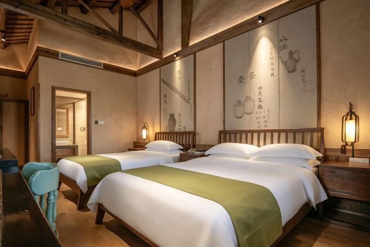 Une pièce de style japonais traditionnel, avec deux lits, des poutres en bois et un lavabo.