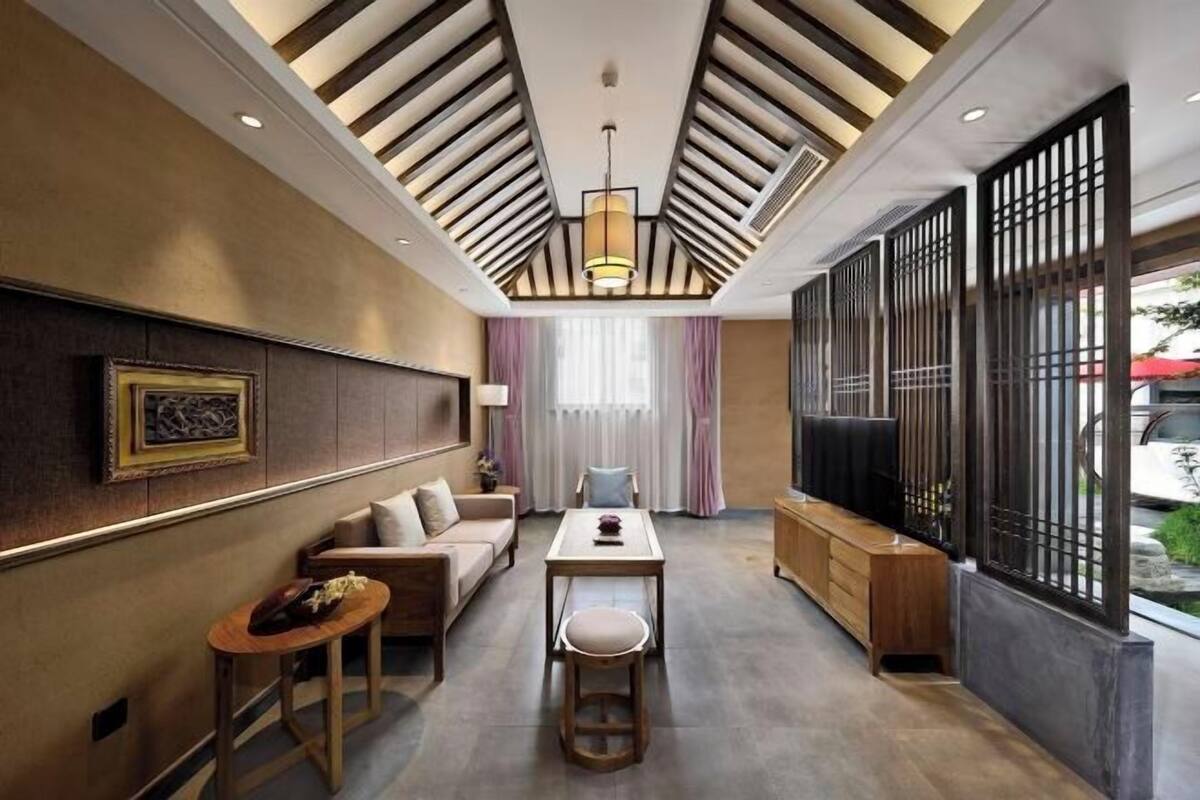 A modern interior with a sofa, table, and chairs, a decorative wall, and a large window with a view.