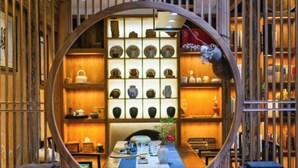 A circular viewing area with a table set for dining, surrounded by shelves of pottery and books.