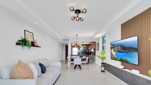 A modern living room with a white sofa, a dining area, and a kitchen in the background. - BeachFront Haven/Isla Verde Prime Location/Parking (Carolina)