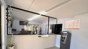 A reception area with a reception desk, a digital display, a notice board, and a small plant. - BAY INN (Tampa)