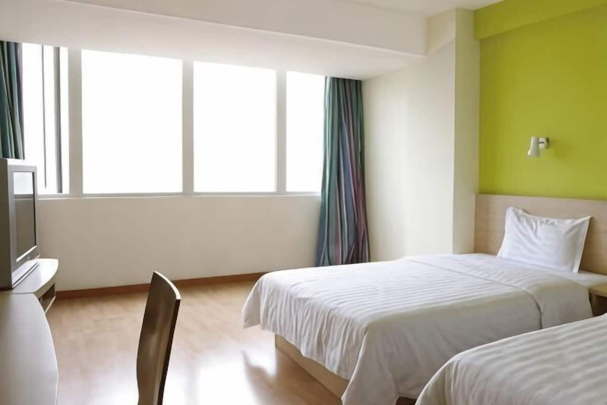 Habitación de hotel con dos camas, un escritorio y un televisor.