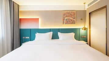Ein Hotelzimmer mit einem großen Bett, einem dunkelblauen Kopfteil, einem Wandbild und einem Nachttisch mit einer Lampe.