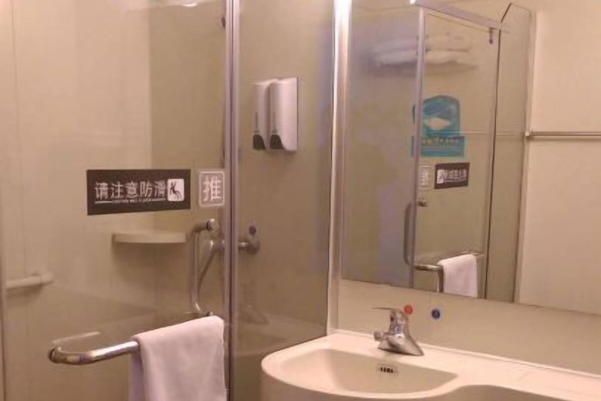 Een badkamer met een douchecabine van glas, een wastafel, een toilet en een spiegel.