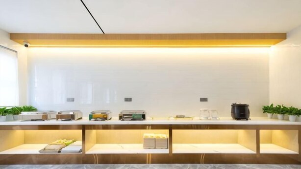 A reception area with a marble floor, a reception desk, a flat-screen TV, and a coffee machine. - 7Days Inn Chain Hotel (Beijing Huairou) (Beijing)