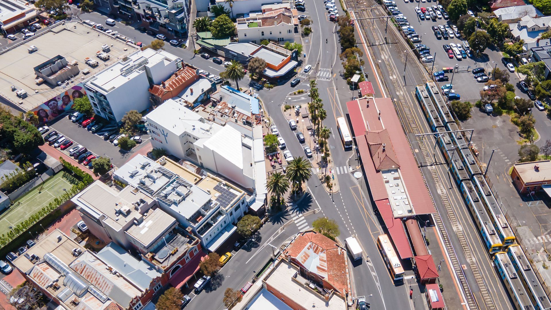 Vista aérea de um cruzamento urbano com edifícios, estradas e uma linha de trem.