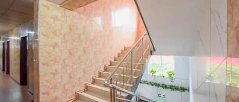 A staircase with a marble wall and metal railing, leading to a lower level.