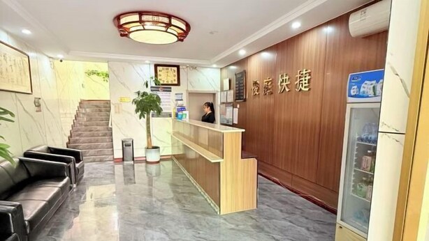 A hotel reception area with a marble floor, a reception desk, a staircase, and a wall-mounted clock. - Shijiazhuang Junting Express Hotel (Shijiazhuang)