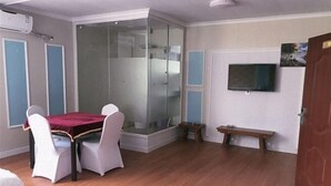 A room with a glass partition, a television, a wooden bench, and a dining table with chairs. - Shijiazhuang Junting Express Hotel (Shijiazhuang)