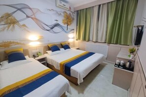 Una camera d'albergo con due letti, un comodino, una scrivania con un bollitore e vista sul tramonto dalla finestra.