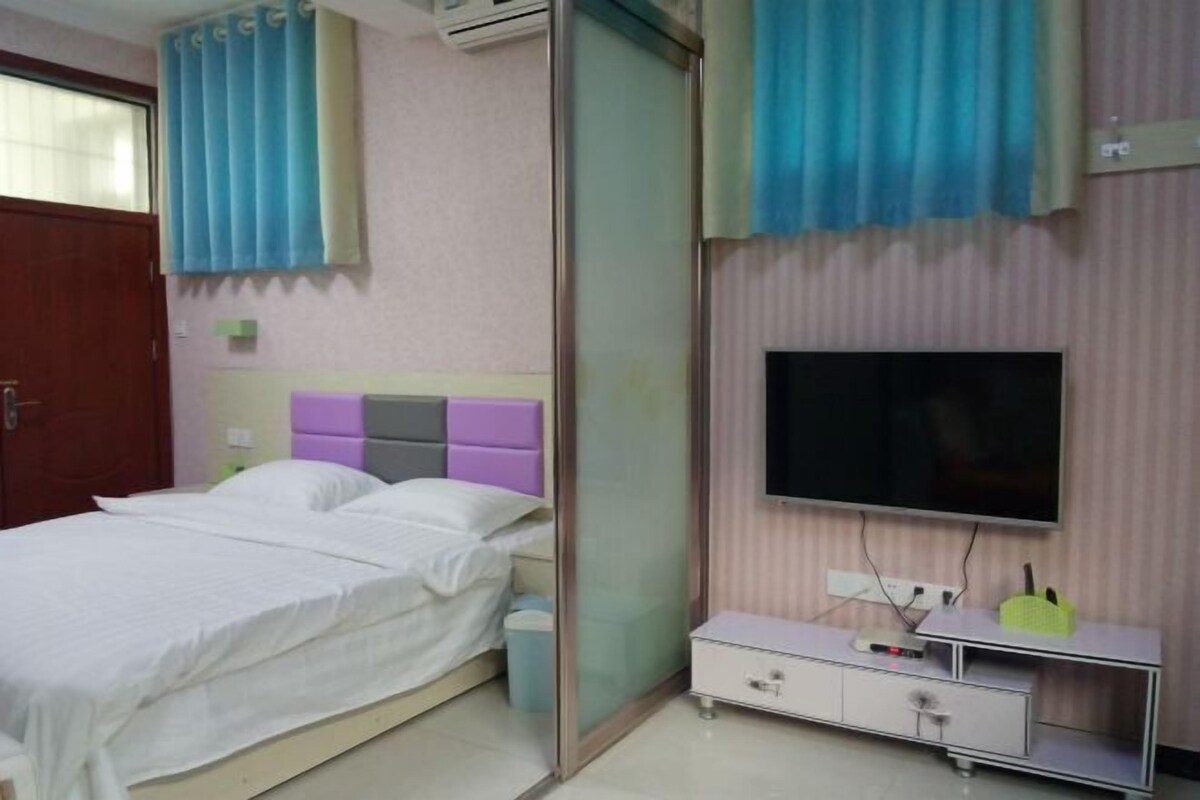 A bedroom with a bed, a TV, a bedside table, and a wardrobe.