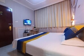 A hotel room with a bed, a television, a desk, and a window with curtains. - Garden Hotel (Sankong Scenic Spot) (Qufu)