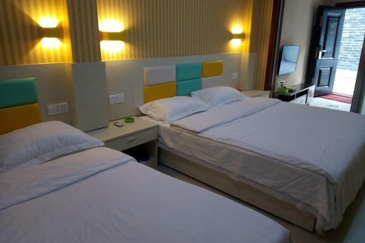 A hotel room with two beds, a bedside table, a mirror, and a door leading to a balcony.