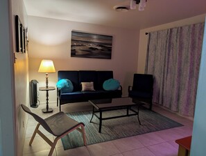 A living room with a sofa, a chair, a coffee table, a lamp, and a painting on the wall. -  3-bedroom Make yourself home while in  Rockdale B (Rockdale)