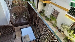 Un balcon agrémenté de meubles en osier et de plantes en pot.
