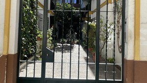 Une entrée fermée par un portail donnant accès à un immeuble, avec une plaque portant le numéro 22 au-dessus du portail.