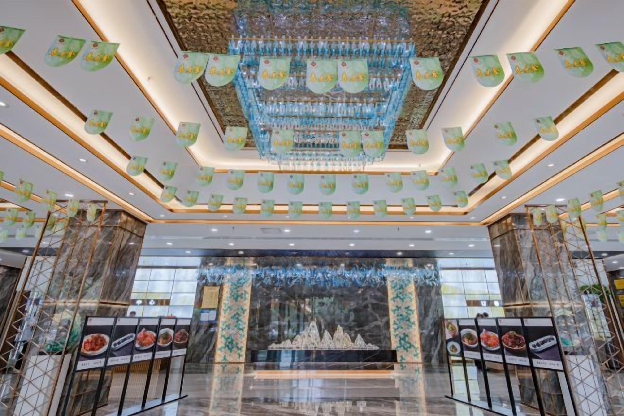 A spacious lobby with a grand chandelier, marble flooring, and a central fountain.