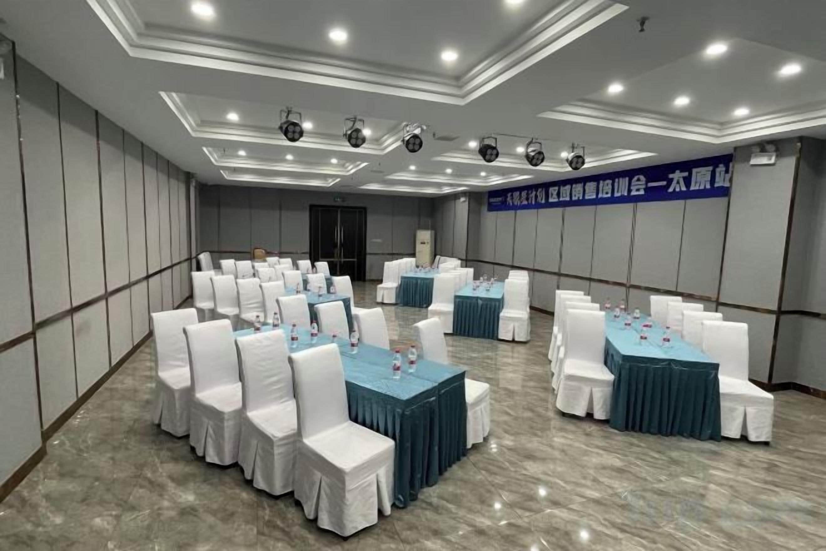 Un salón de conferencias con varias mesas y sillas, suelo de mármol e iluminación empotrada en el techo.