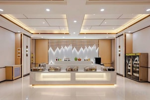 A modern hotel lobby with a reception desk, seating area, and a decorative wall.