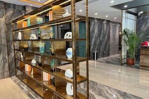 A modern interior with a glass and metal shelving unit displaying various decorative items.