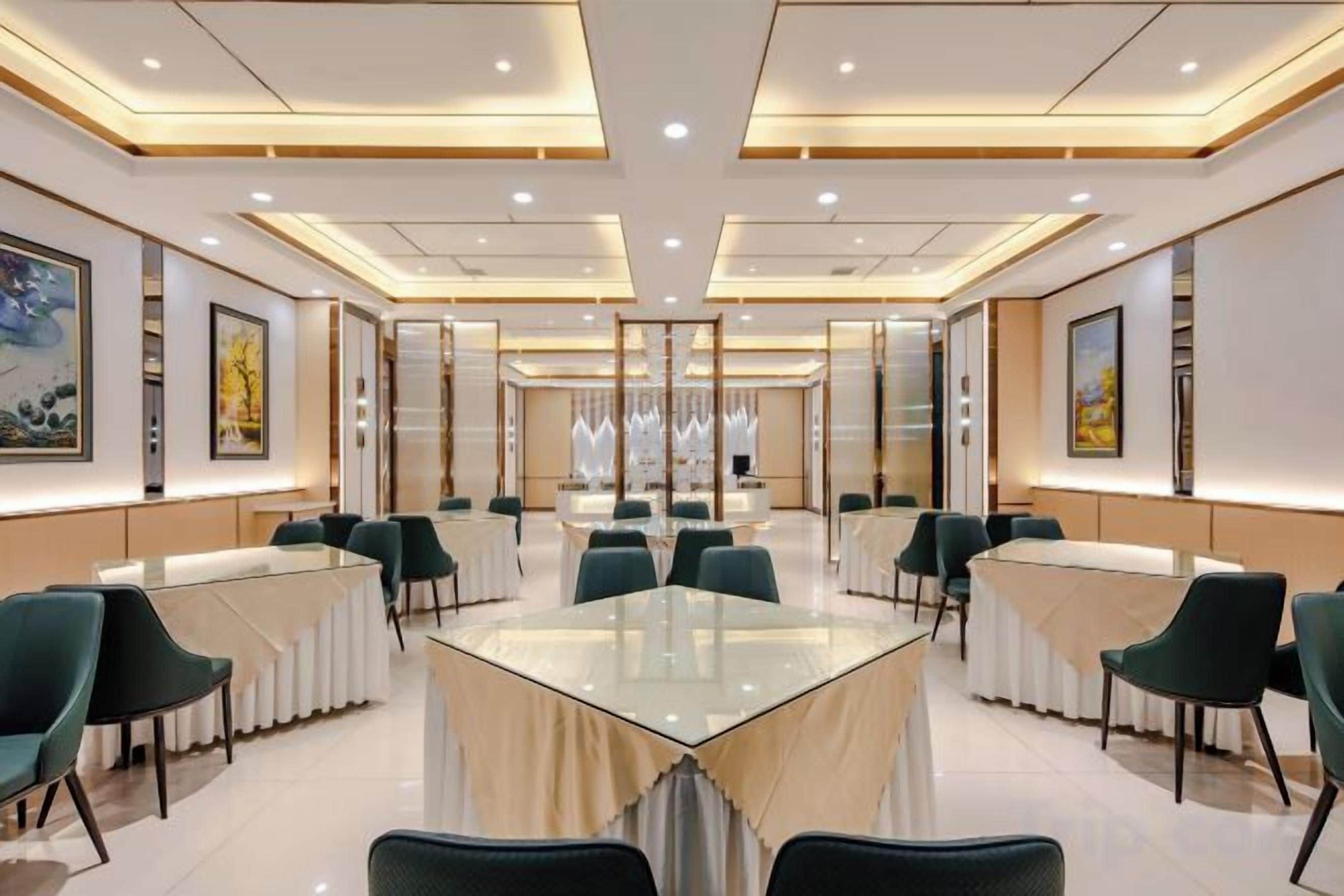 A conference room with a glass table, green chairs, and framed artwork on the walls.