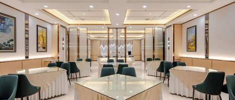 A conference room with a glass table, green chairs, and framed artwork on the walls.