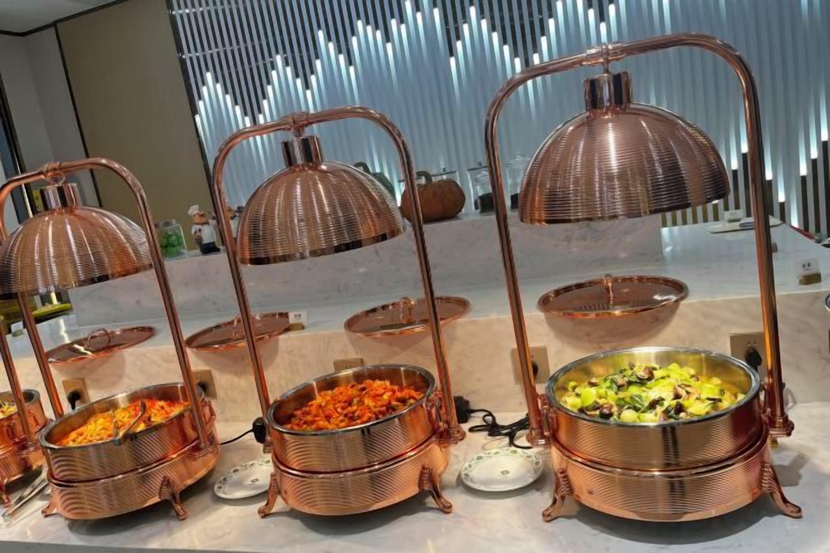 A buffet setup with copper serving stands and food containers.