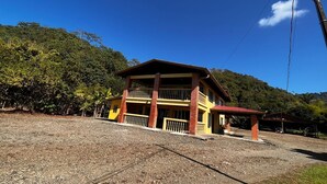 A two-story building with a balcony, surrounded by trees and a clear sky. - Casa Mangostan (Savegre)