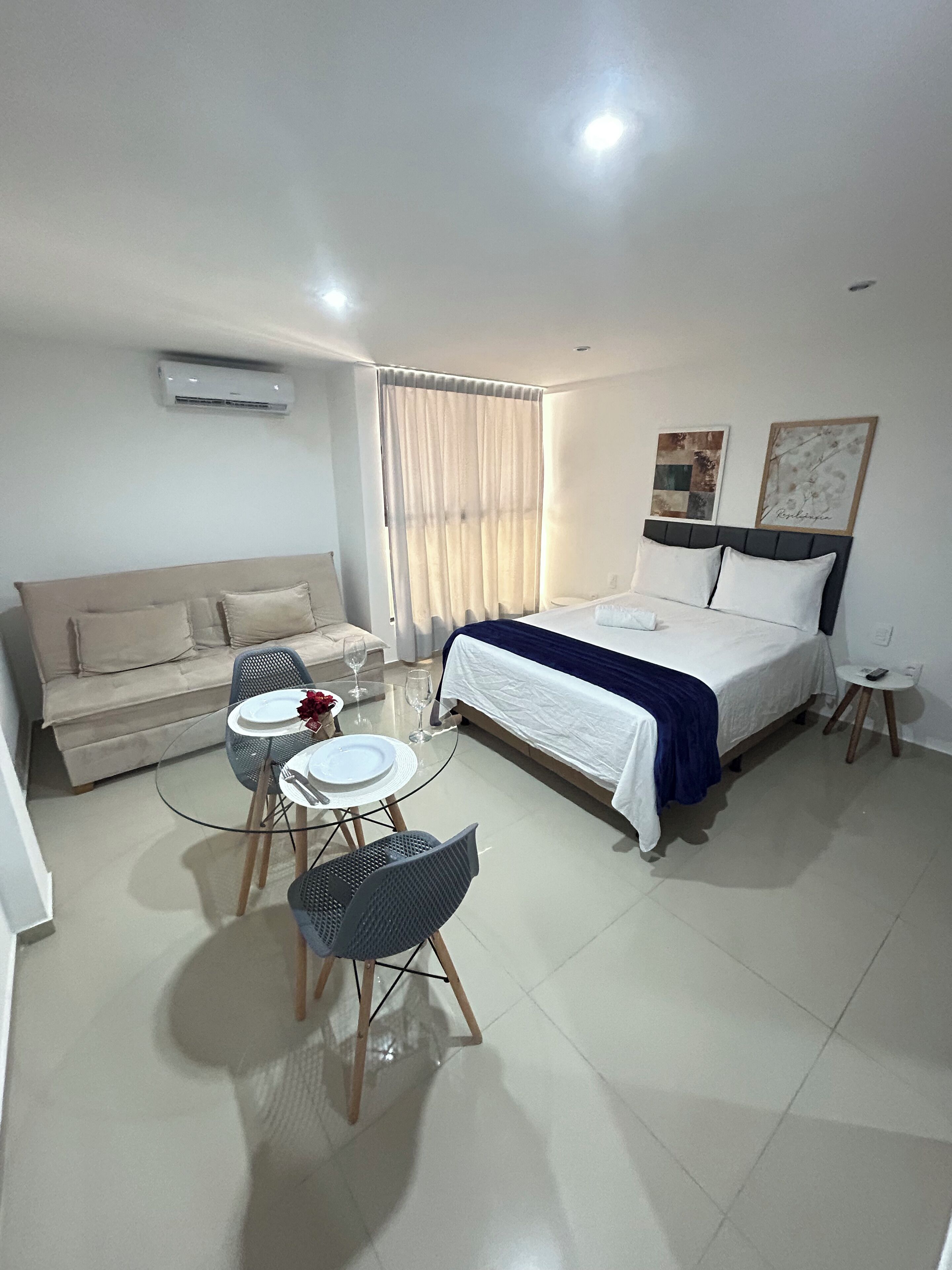 Une chambre d’hôtel comprenant un lit, un canapé, une petite table ronde avec des chaises, une table en verre et une chaise.