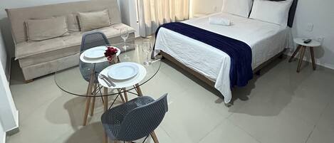 Une chambre d’hôtel comprenant un lit, un canapé, une petite table ronde avec des chaises, une table en verre et une chaise.